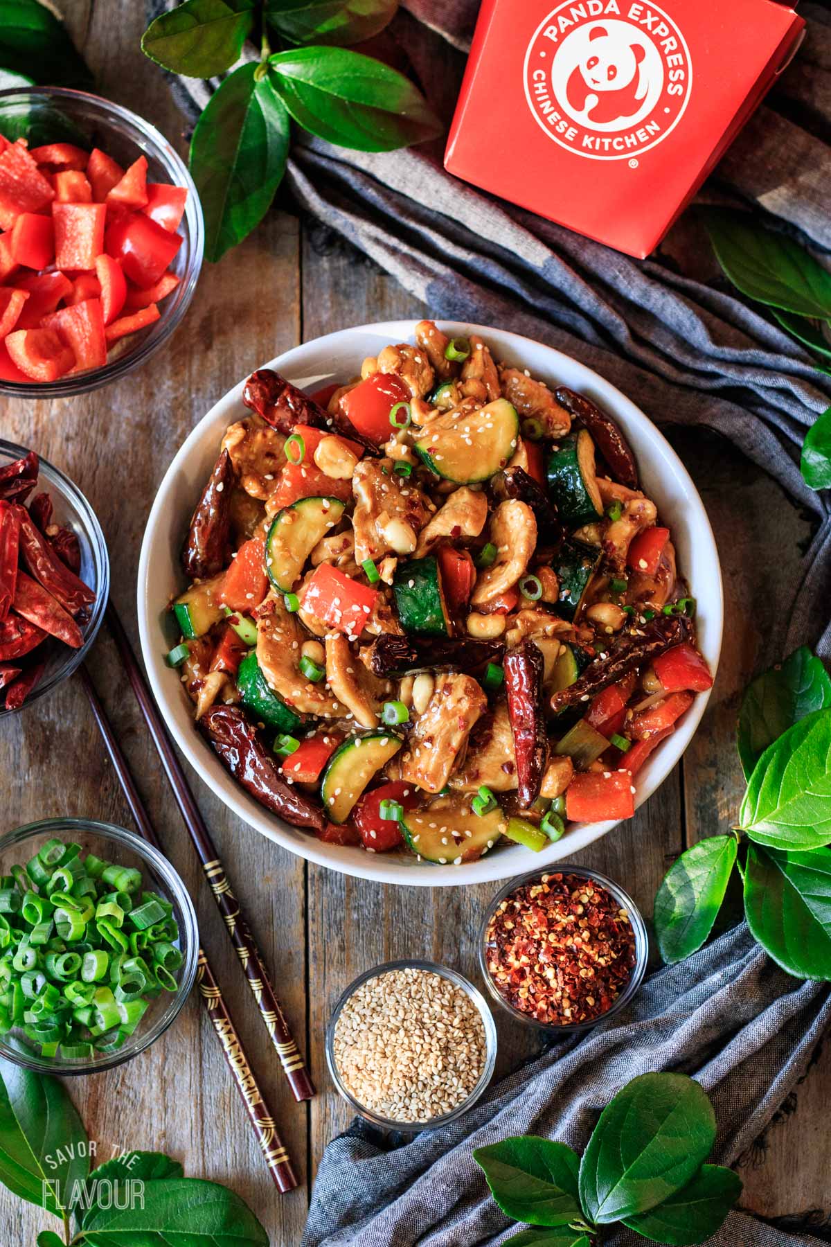 bowl of Kung Pao chicken with chopsticks and bowls of garnishes