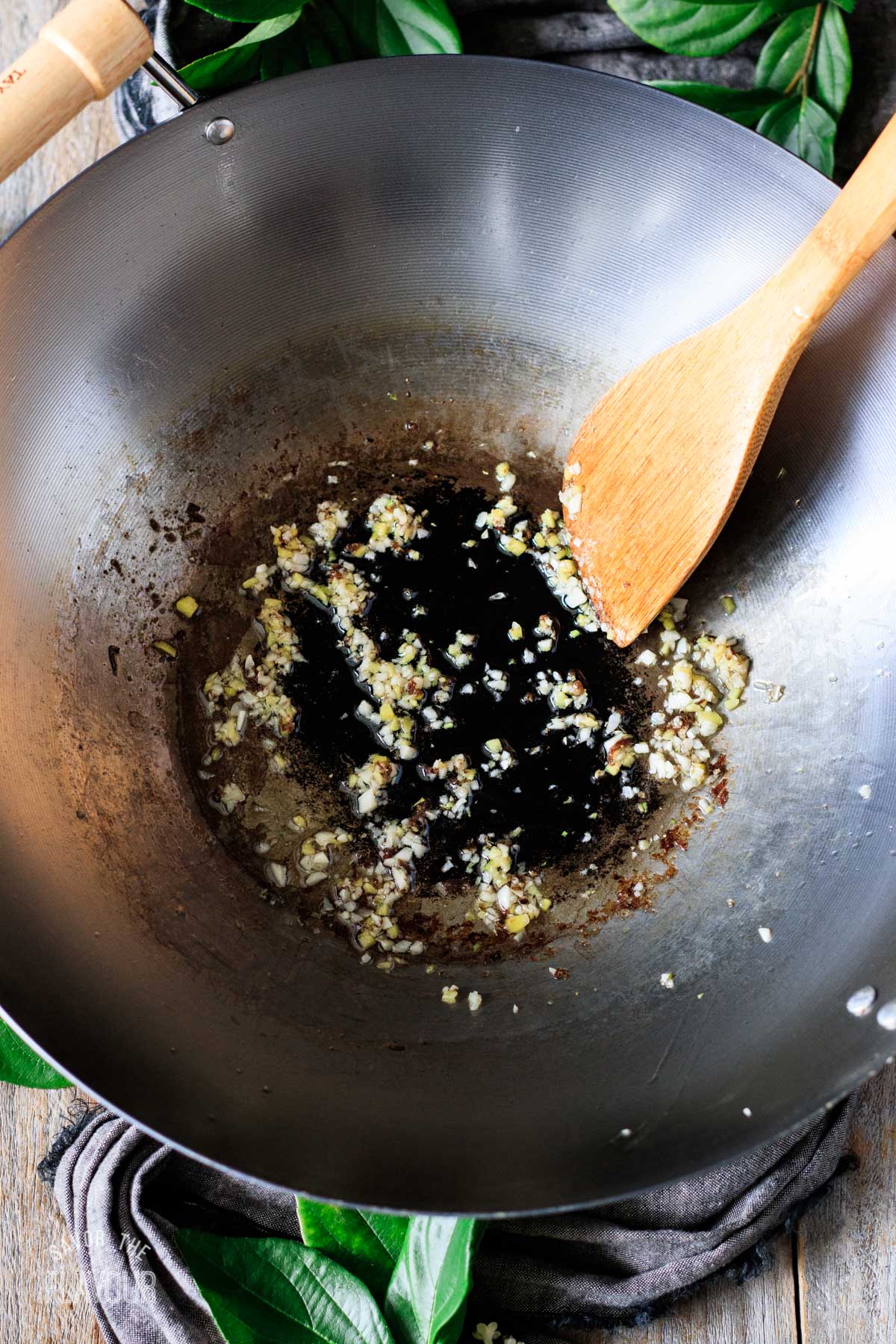 person stirring minced garlic and ginger in a wok
