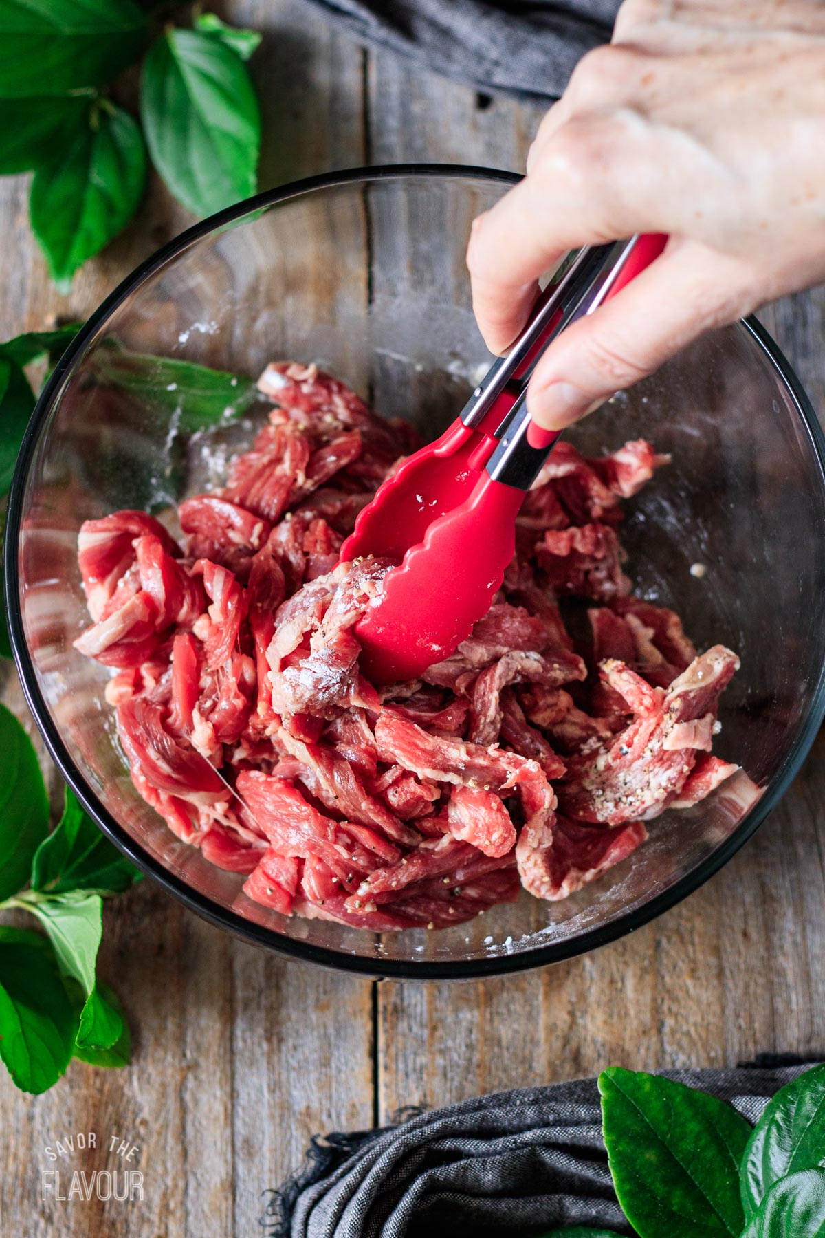 person mixing sliced raw beef with the marinade