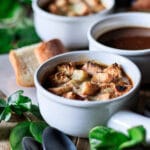 bowl of Panera French onion soup with spoons and a baguette chunk