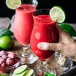 person holding a glass of virgin raspberry daiquiri