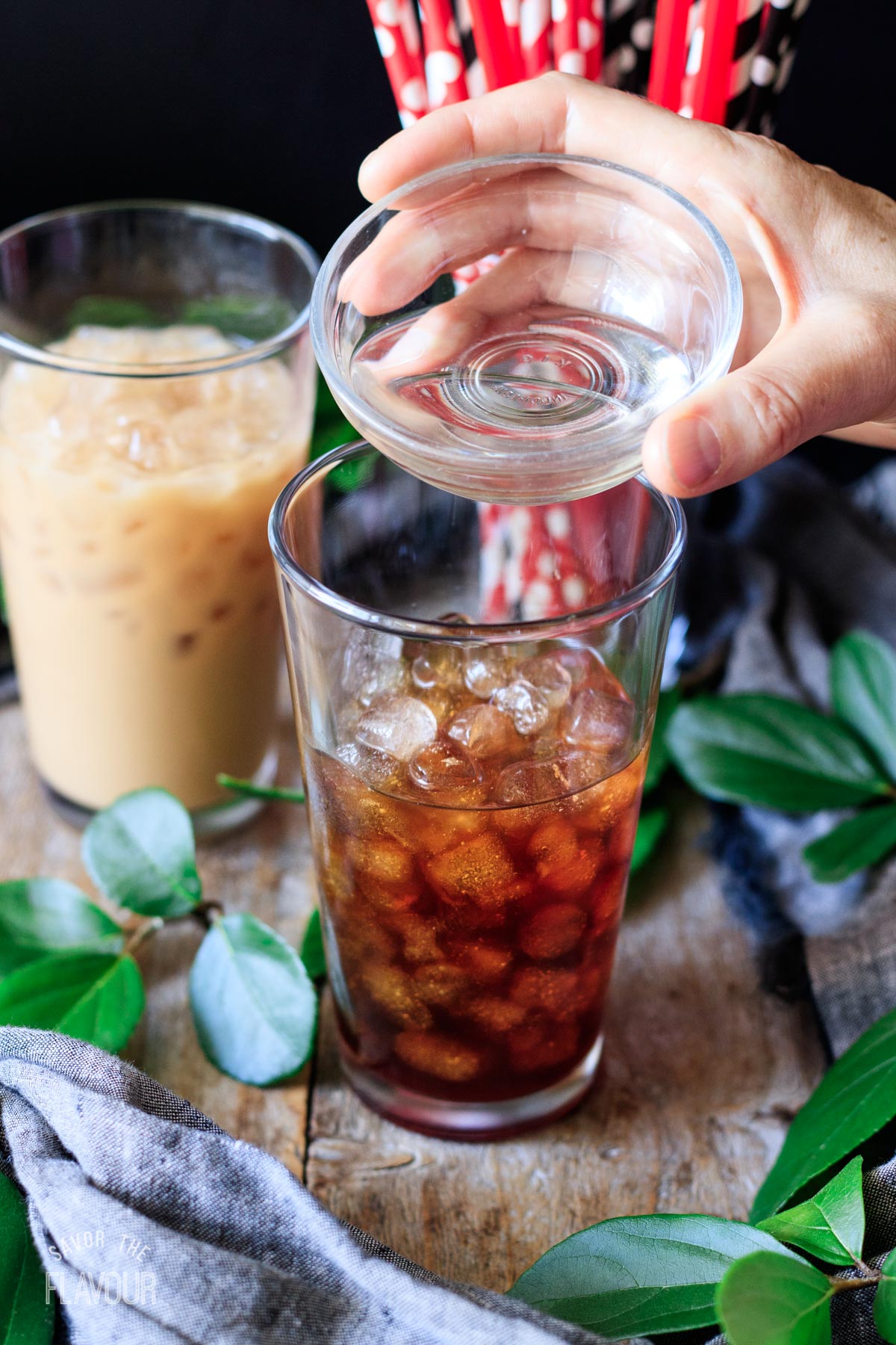 person pouring simple syrup into a glass of coffee