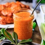 glass mason jar of buffalo sauce with a spoon