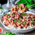 person holding a large spoonful of red beans and rice