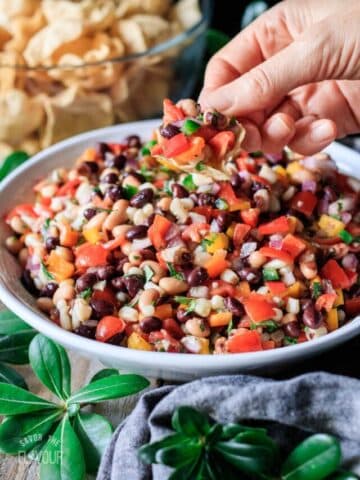 person dipping a chip into cowboy caviar