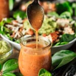 person pouring a spoonful of Chipotle honey dressing into a jar