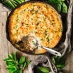 large cast iron skillet of shepherd's pie with a spoon