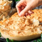 person holding a scoop of buffalo chicken dip in a chip