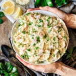 person holding a bowl of ham and peas bow tie pasta