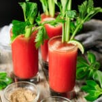 three Caesar mocktails with a bowl of celery salt