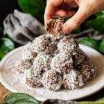 person holding half of a date coconut protein ball