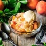 bowl of peach cobbler with two black spoons
