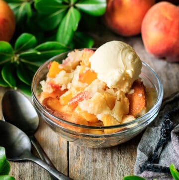 bowl of peach cobbler with two black spoons