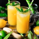 two glasses of mango lemonade with a citrus reamer