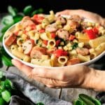 person holding a bowl of pear, sausage, and gouda rigatoni