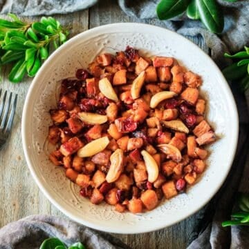 white bowl of roasted sweet potatoes with cranberries