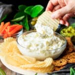 person dipping a chip into the dill pickle dip