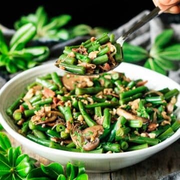 person holding a spoonful of green beans and mushrooms