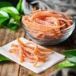 glass bowl of grapefruit peels with some on parchment paper.
