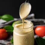 pouring a spoonful of creamy salsa dressing into a glass jar.