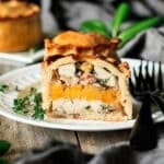 half of a chicken, bacon, and apricot pie on a white plate.