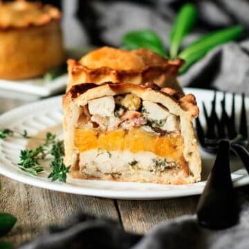 half of a chicken, bacon, and apricot pie on a white plate.