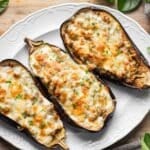 three stuffed eggplant halves on a white platter.