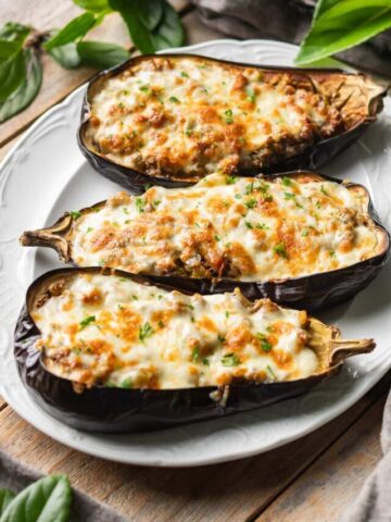 three stuffed eggplant halves on a white platter.