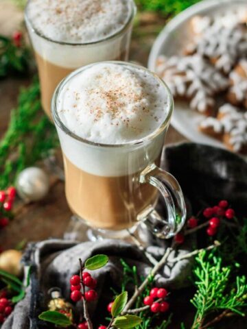 two gingerbread lattes with sprigs of red berries.