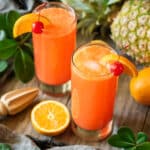 two glasses of Cinderella mocktail with a citrus reamer.