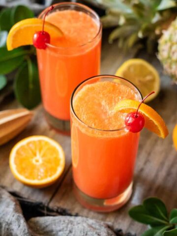 two glasses of Cinderella mocktail with a half of an orange.