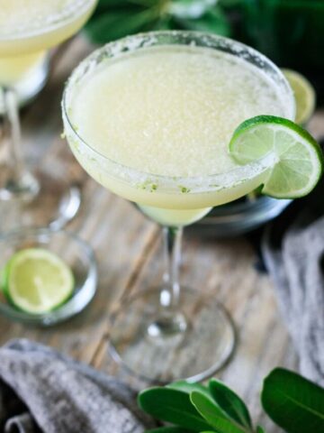 two frozen lime margaritas with bowls of limes.