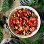 bowl of tomato olive salad with two spoons.