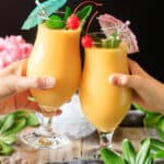 people toasting with two mango daiquiris.