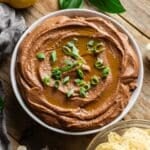 bowl of black bean hummus garnished with green onion.