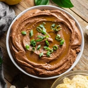 bowl of black bean hummus garnished with green onion.