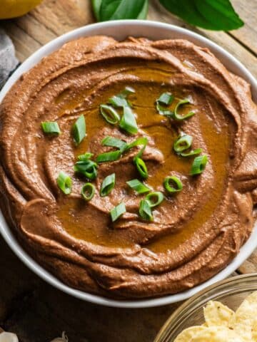 bowl of black bean hummus garnished with green onion.