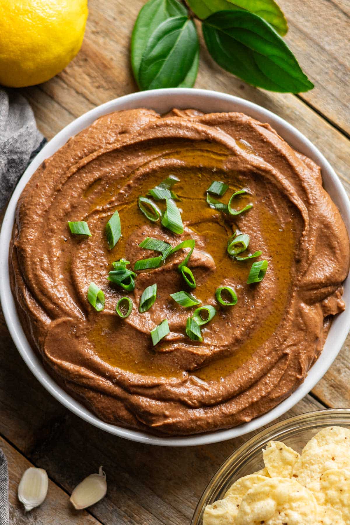 bowl of black bean hummus garnished with green onion and oil.