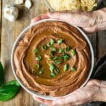 person holding a bowl of black bean hummus.