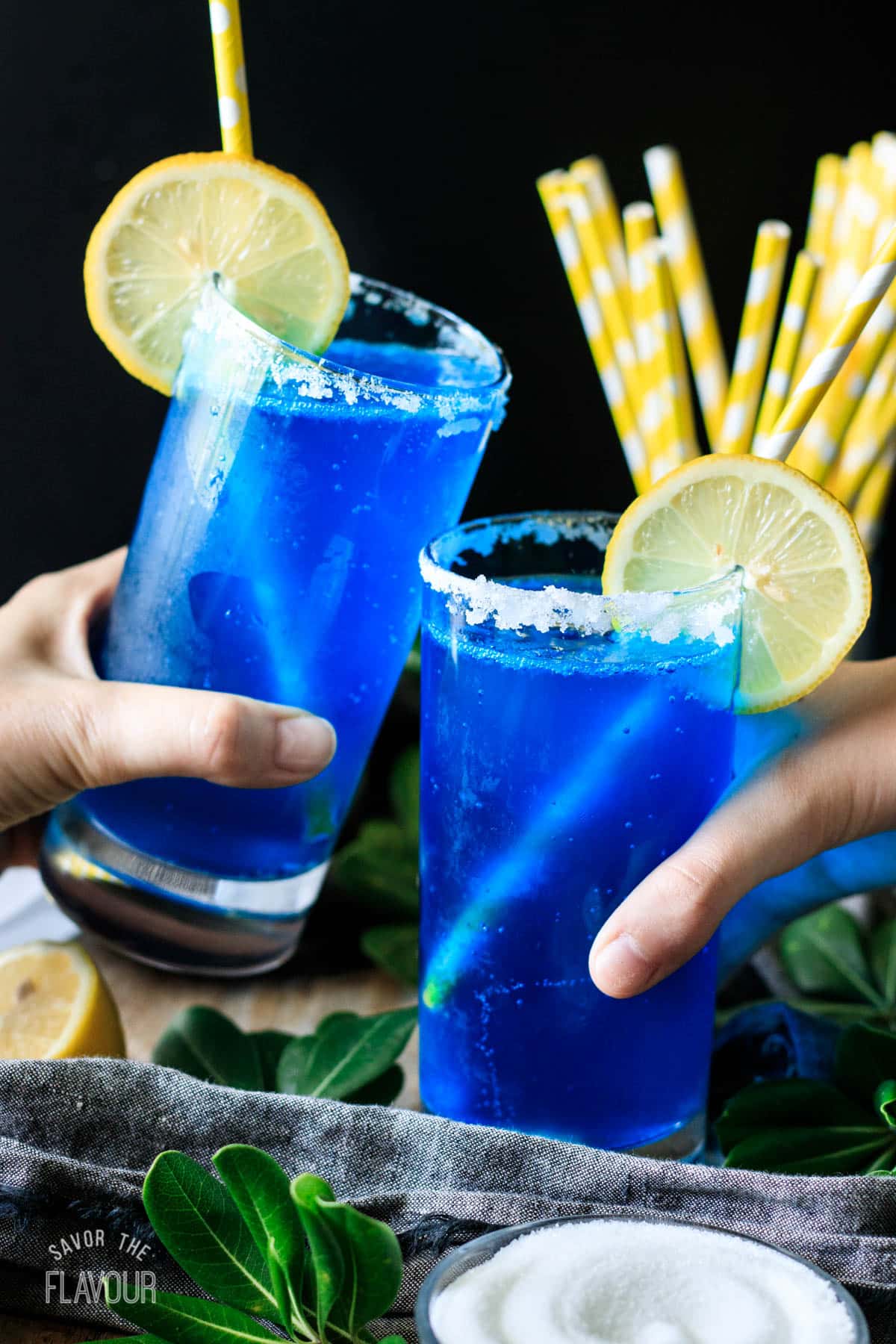 people doing a toast with two glasses of blue lagoon mocktail.