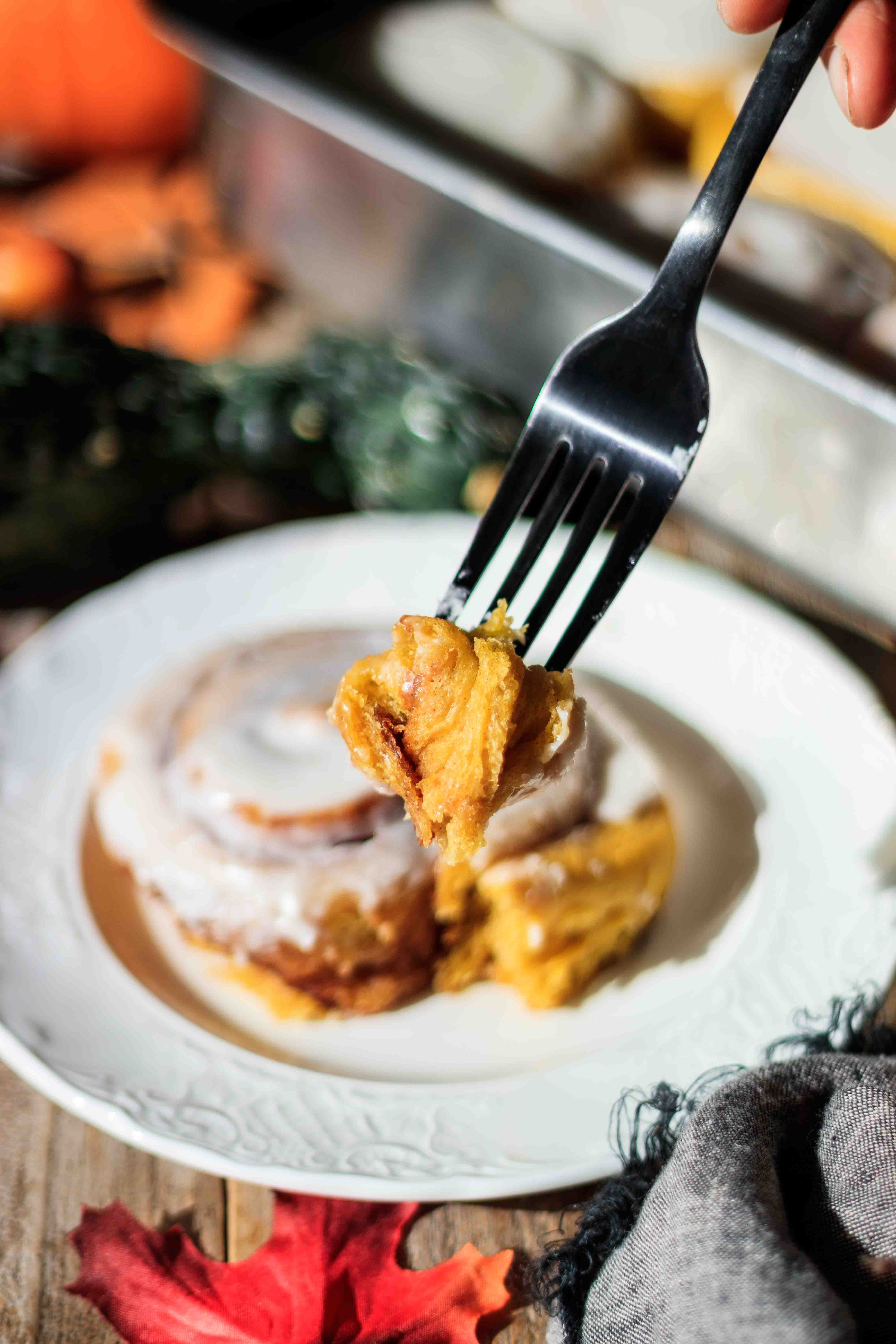 holding a forkful of vegan pumpkin cinnamon roll.