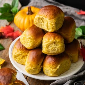 plate of pumpkin dinner rolls in a stack.