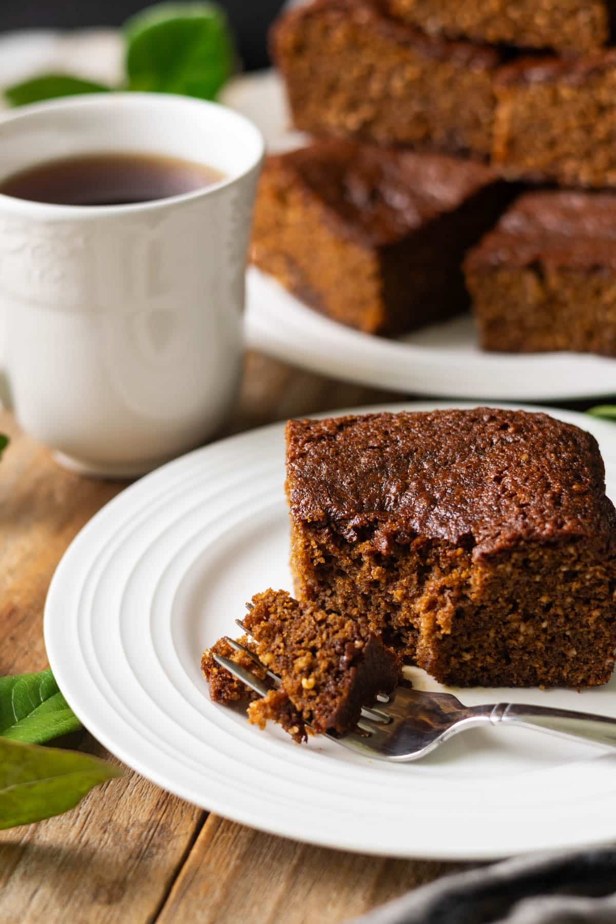 slice of parkin on a plate with a fork and cup of tea.