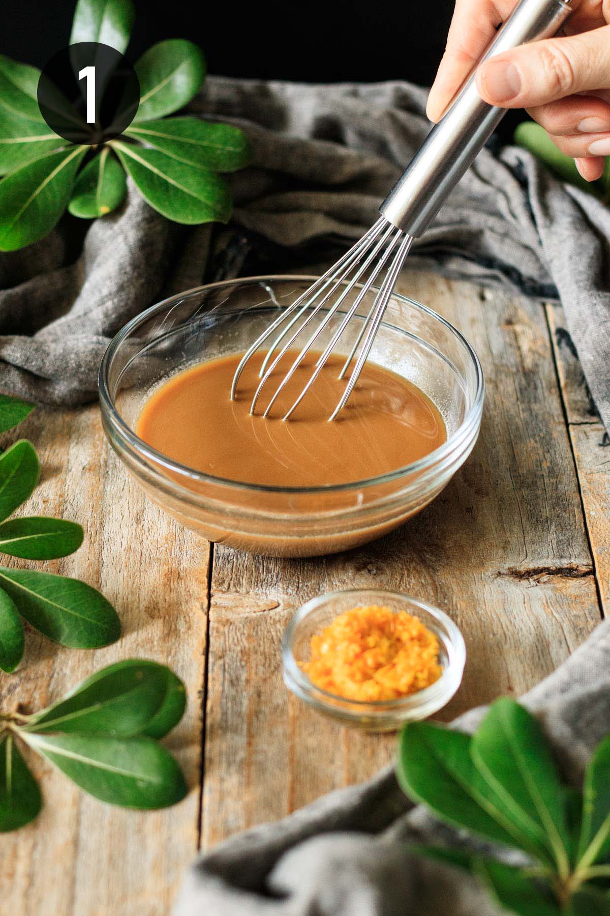 whisking the sauce ingredients in a glass bowl.