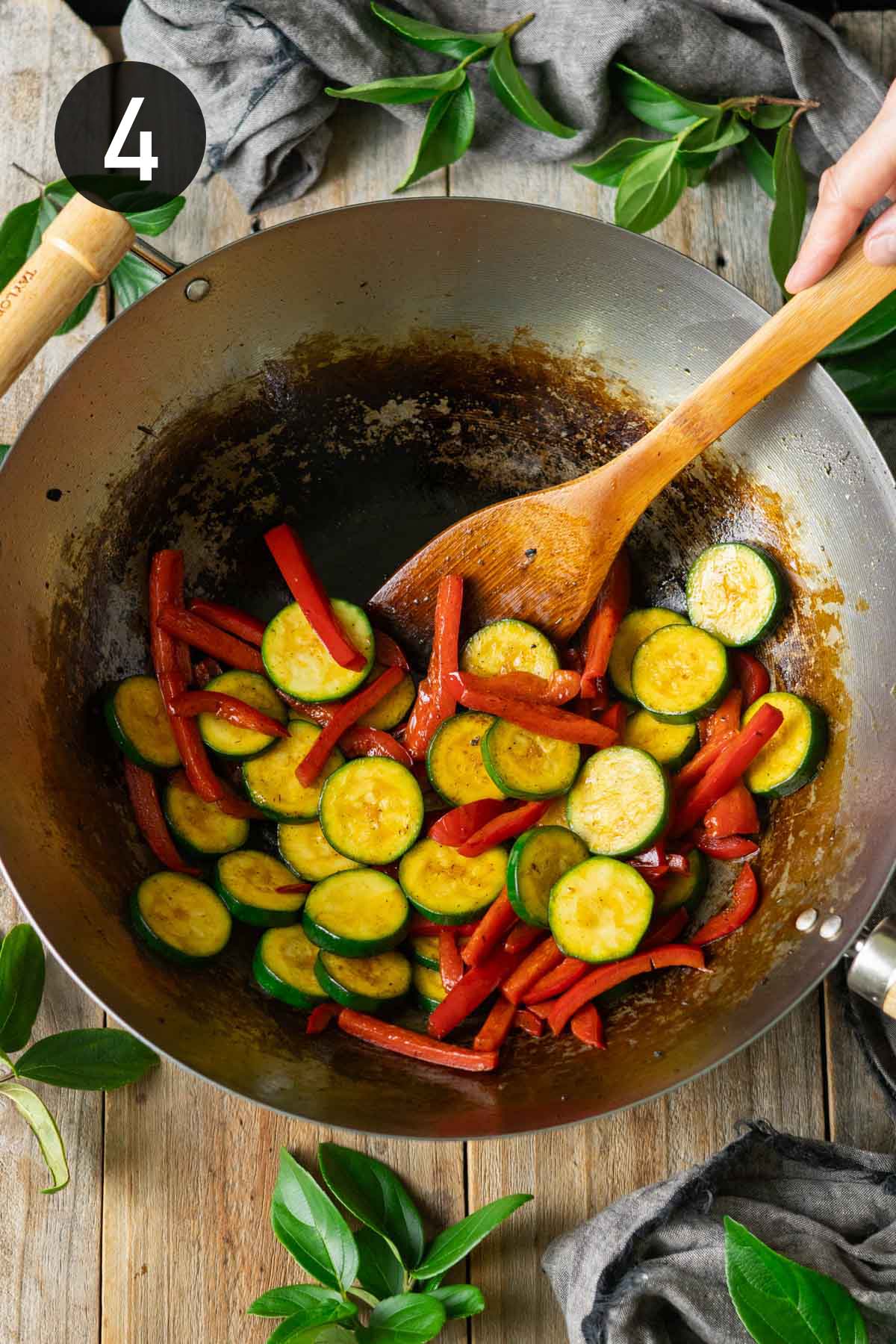 cooking the zucchini and peppers in a wok.
