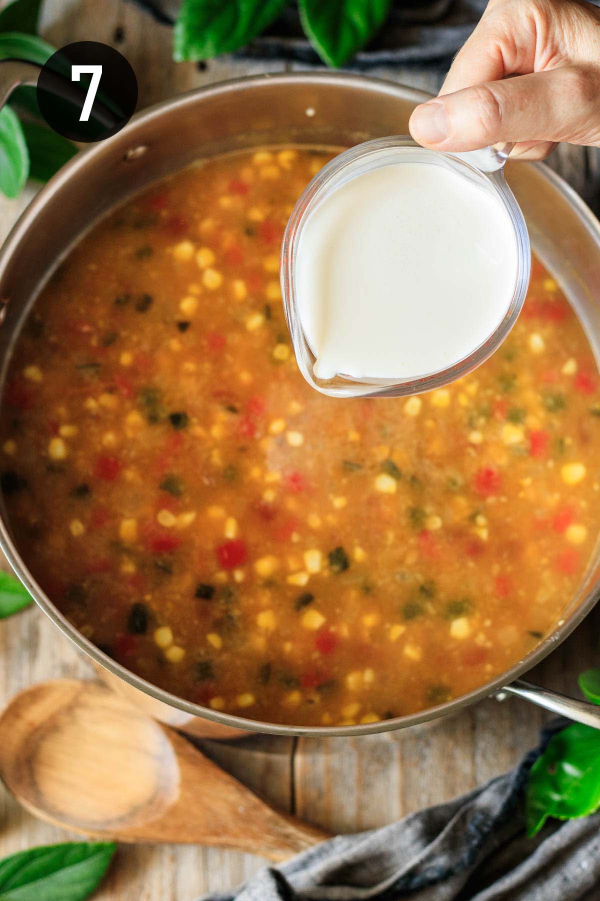 pouring heavy cream into a pot of chowder.