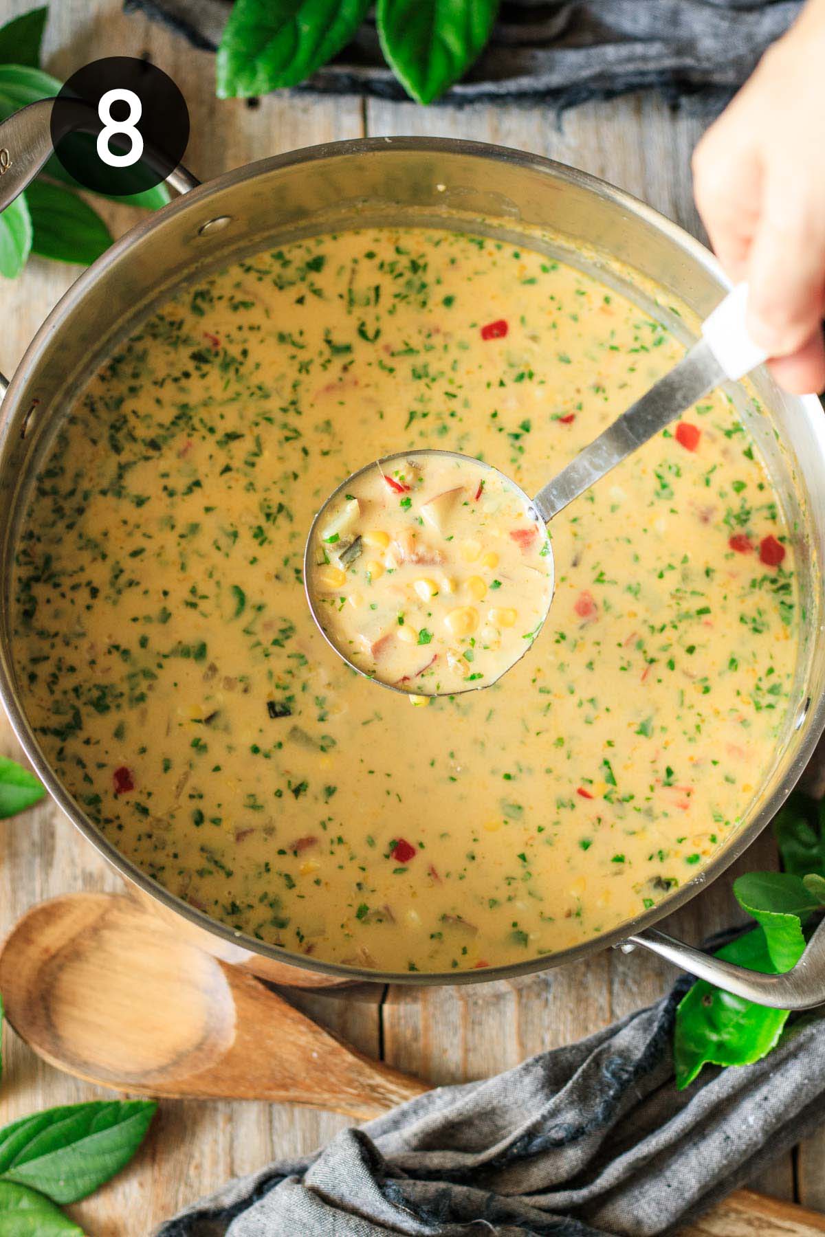 holding a ladleful of corn chowder.