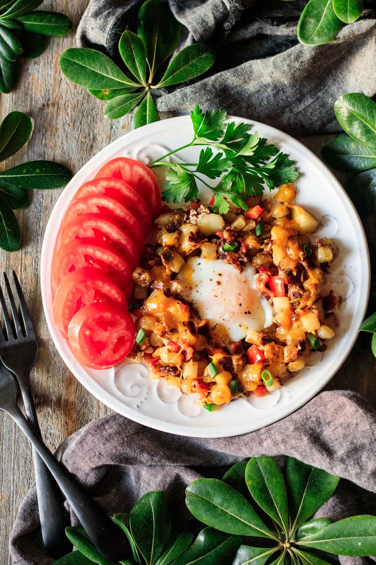 plate of skillet breakfast hash with sliced tomatoes and parsley.