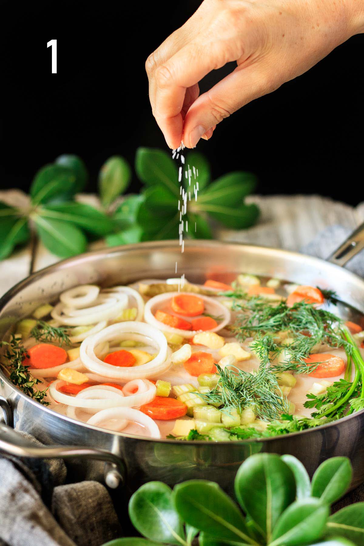 sprinkling kosher salt into a pan of chicken and veggies.