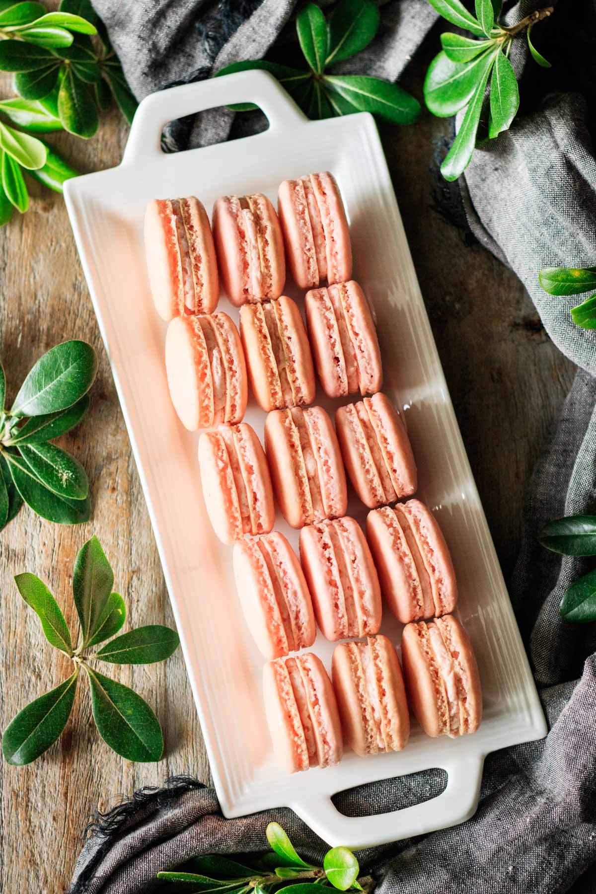 rows of strawberry macarons on a rectangular white plate.